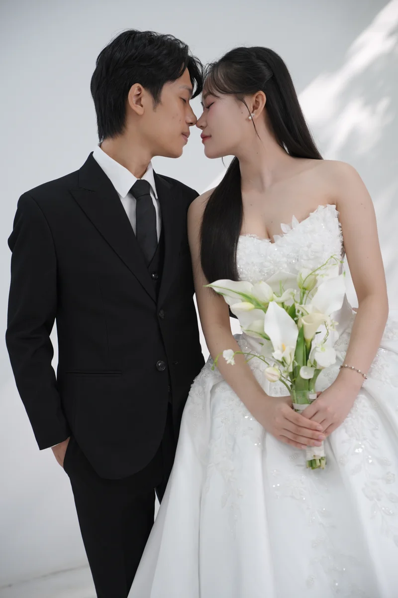 Duy và Ánh nghiêng đầu gần nhau, cô dâu cầm bó hoa trắng