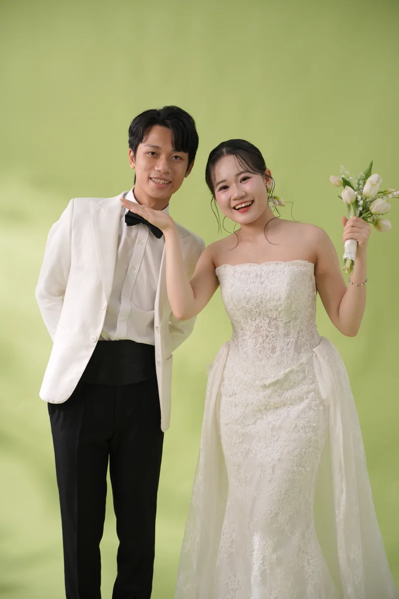 Duy và Ánh cười tươi bên nhau trên phông xanh lá